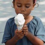 Young girl eating a vanilla ice cream cone